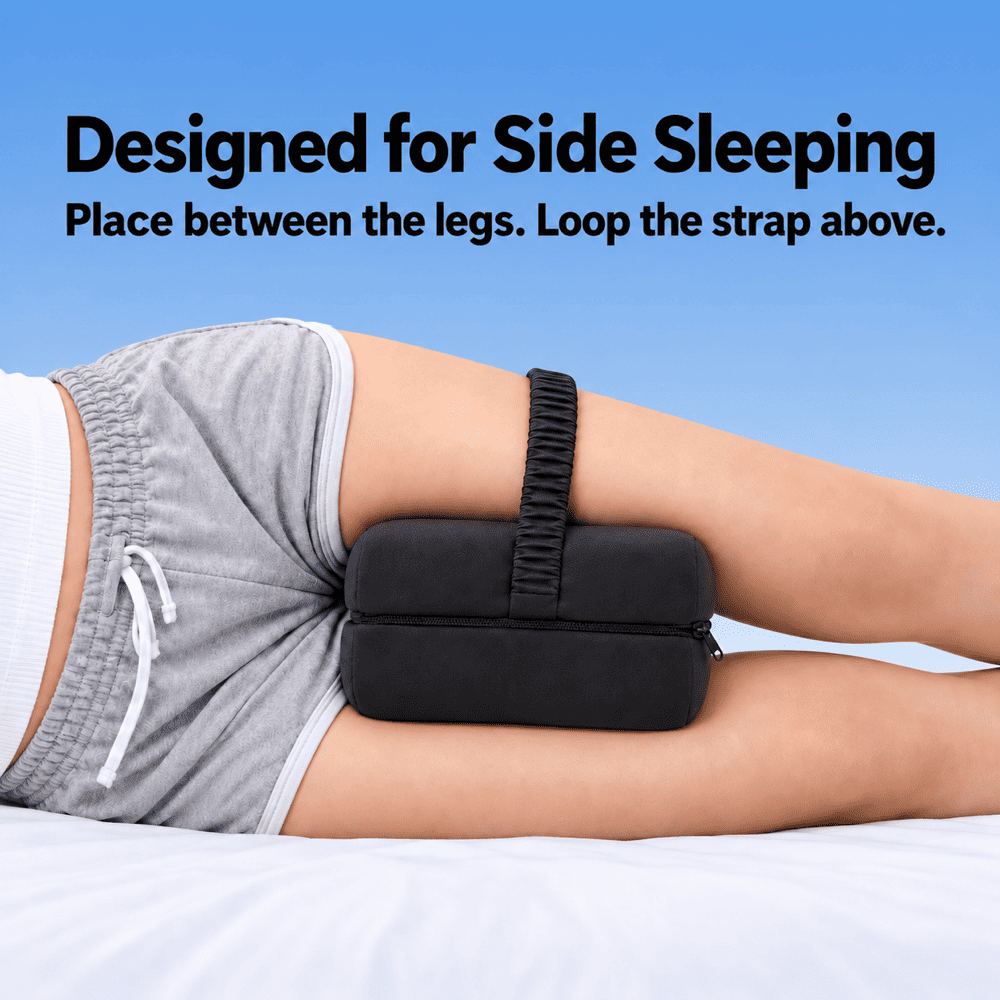 A person lying on a bed demonstrates a black side-sleeping lumbar support pillow placed between the legs, with text at the top reading 'Designed for Side Sleeping' and instructions on how to place the strap.