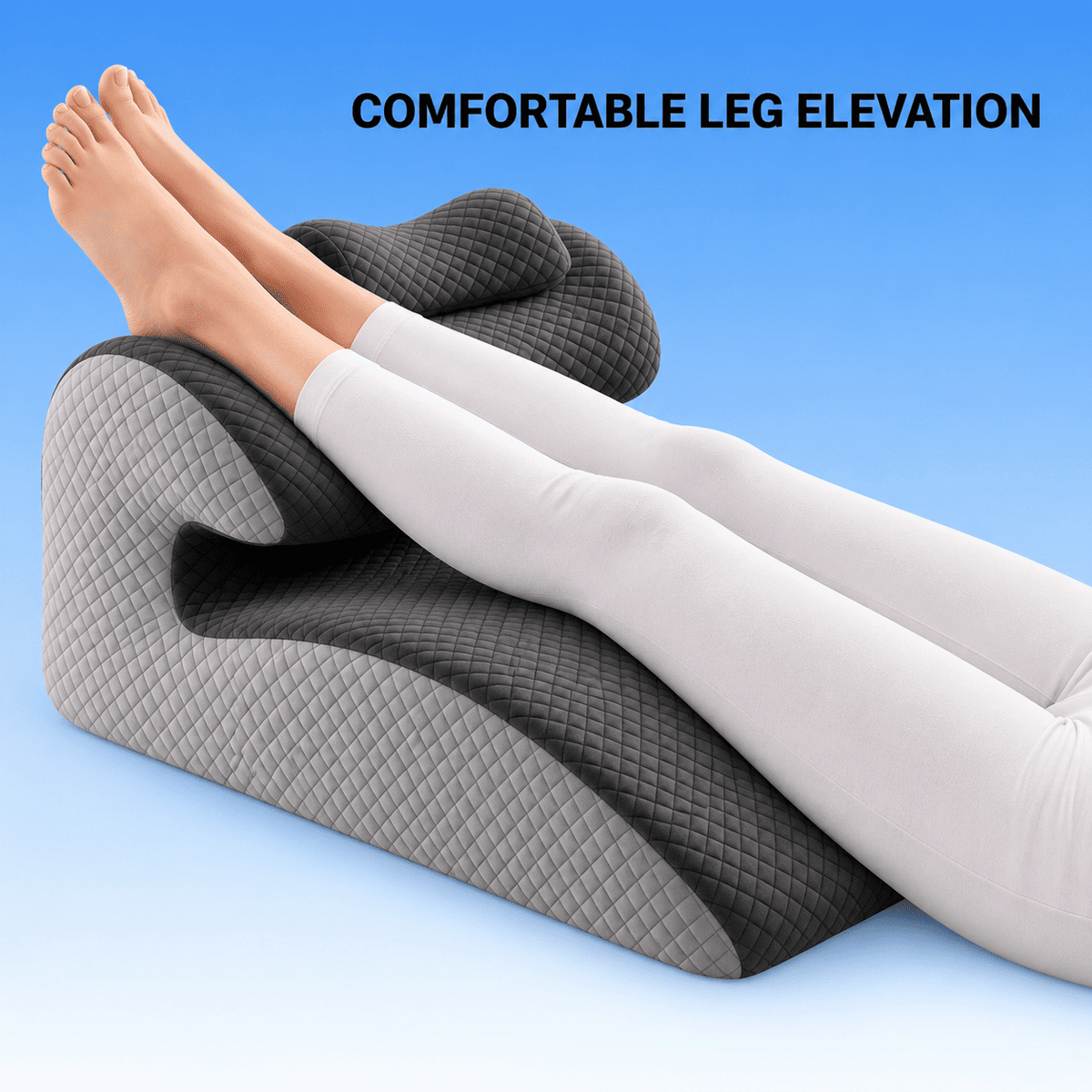 A gray and black quilted contoured leg elevation pillow with a person's legs resting on it, set against a blue gradient background with the text 'COMFORTABLE LEG ELEVATION'.
