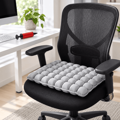 A light gray segmented mesh office chair cushion resting on a black mesh office chair in a bright, modern home office setting.