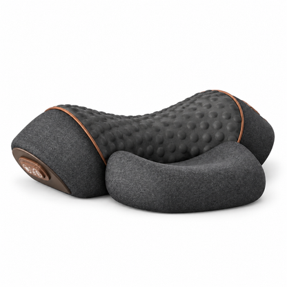 A dark gray massage pillow with a textured, dimpled surface and smooth fabric sides, featuring a small circular control button on one end and thin brown piping details, shown on a white background.