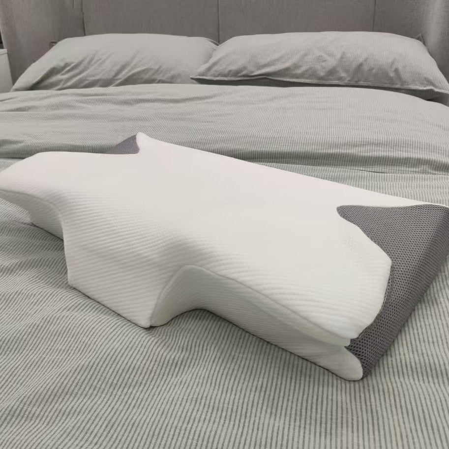 White and gray wedge-shaped pillow on a bed with gray bedding.