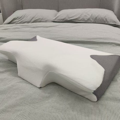 White and gray wedge-shaped pillow on a bed with gray bedding.